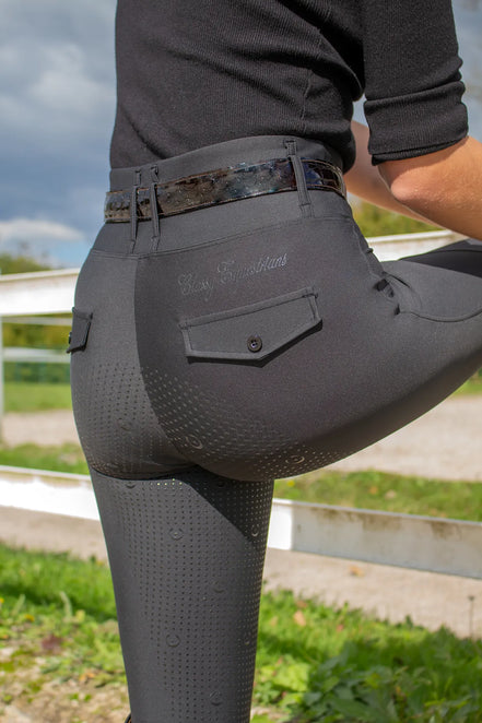 Person wearing classy equestrians black riding tights with a visible brand logo in an outdoor setting.