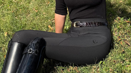 Person sitting on the grass with classy equestrians blach riding thights